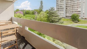 Un balcón con vista a un parque verde y un edificio residencial alto.