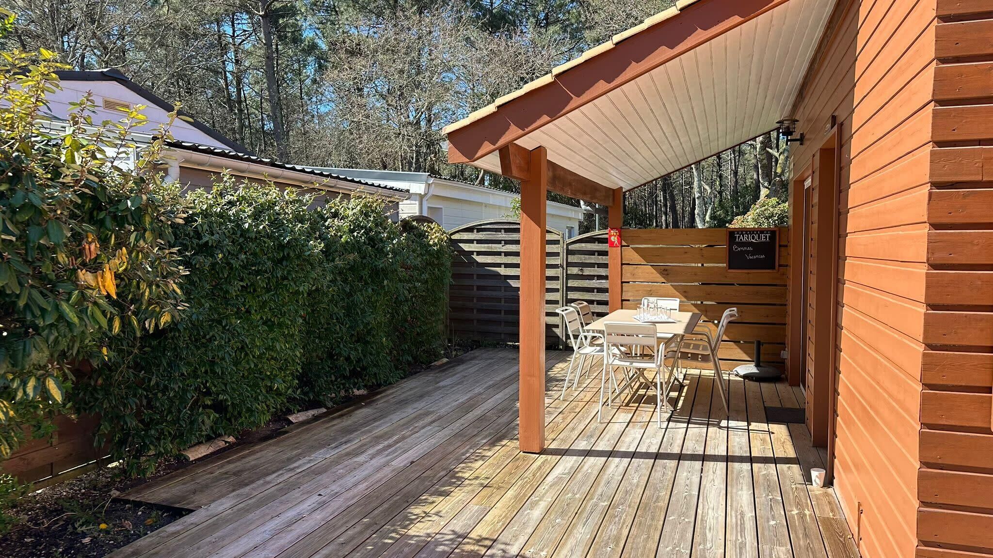Une terrasse en bois dotée d’un espace salon couvert, d’une clôture en bois et d’un panneau indiquant la présence d’un restaurant.