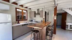 A modern kitchen with a wooden island, bar stools, a built-in oven, and a microwave.