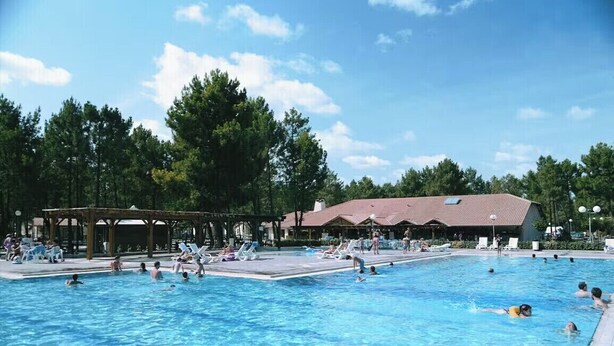 A large outdoor swimming pool surrounded by trees and a pavilion.