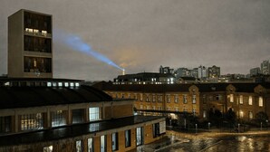 Paesaggio urbano notturno con un edificio moderno e palazzi più antichi in mattoni.