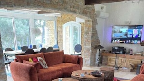 Una sala de estar con pared de piedra, un sofá, una mesa de centro y un televisor.