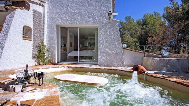 Un área de spa con un jacuzzi, puerta de vidrio y un camino de piedra.