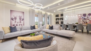 A modern living room with sofas, a coffee table, and a dining area with chairs and a table. - Last Minute Disney Getaway! Private Pool, Game Room & Themed Bedrooms. Book Now! #163613 (Orlando)
