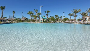 A clear swimming pool with a water slide, surrounded by palm trees and a clear blue sky. - Last Minute Disney Getaway! Private Pool, Game Room & Themed Bedrooms. Book Now! #163615 (Orlando)