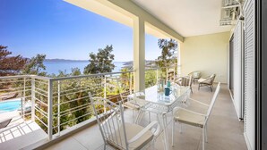 A balcony with a table and chairs, overlooking a pool and a scenic view of the sea and mountains. - Villa Limanaki, Villa Limanaki Lavrion Port (Lavrio)
