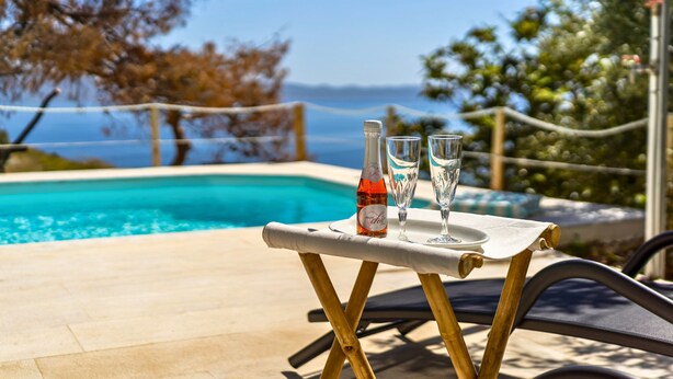 A poolside table with a bottle and glasses, overlooking a pool and a scenic view. - Villa Limanaki, Villa Limanaki Lavrion Port (Lavrio)
