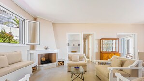 A living room with a fireplace, sofas, a coffee table, and a cabinet. - Villa Limanaki, Villa Limanaki Lavrion Port (Lavrio)
