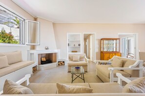 A living room with a fireplace, sofas, a coffee table, and a cabinet. - Villa Limanaki, Villa Limanaki Lavrion Port (Lavrio)