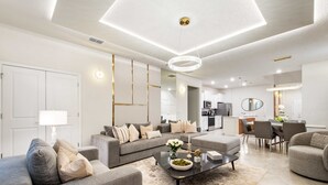 A modern living room with a sofa, coffee table, and dining area. - Last Minute Disney Getaway! Private Pool, Game Room & Themed Bedrooms. Book Now! #163621 (Orlando)