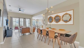 A spacious dining area with a large table and chairs, a ceiling fan, and hexagonal mirrors on the wall. - Last Minute Disney Getaway! Private Pool, Game Room & Themed Bedrooms. Book Now! #163627 (Orlando)