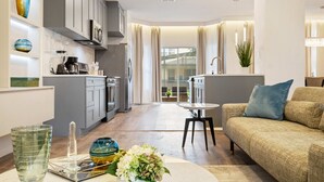 Une cuisine moderne avec des meubles gris, un coin repas comprenant un canapé et une table, et une vue sur un balcon.