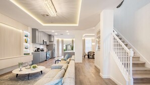 Un vaste espace de vie comprenant un canapé, une table basse et un escalier.