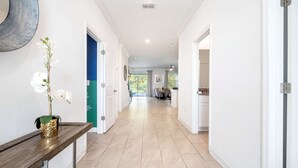 Un pasillo con una consola de madera, una orquídea blanca y una puerta azul.