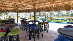 Un patio al aire libre con mesas y taburetes, una piscina y vistas del paisaje.
