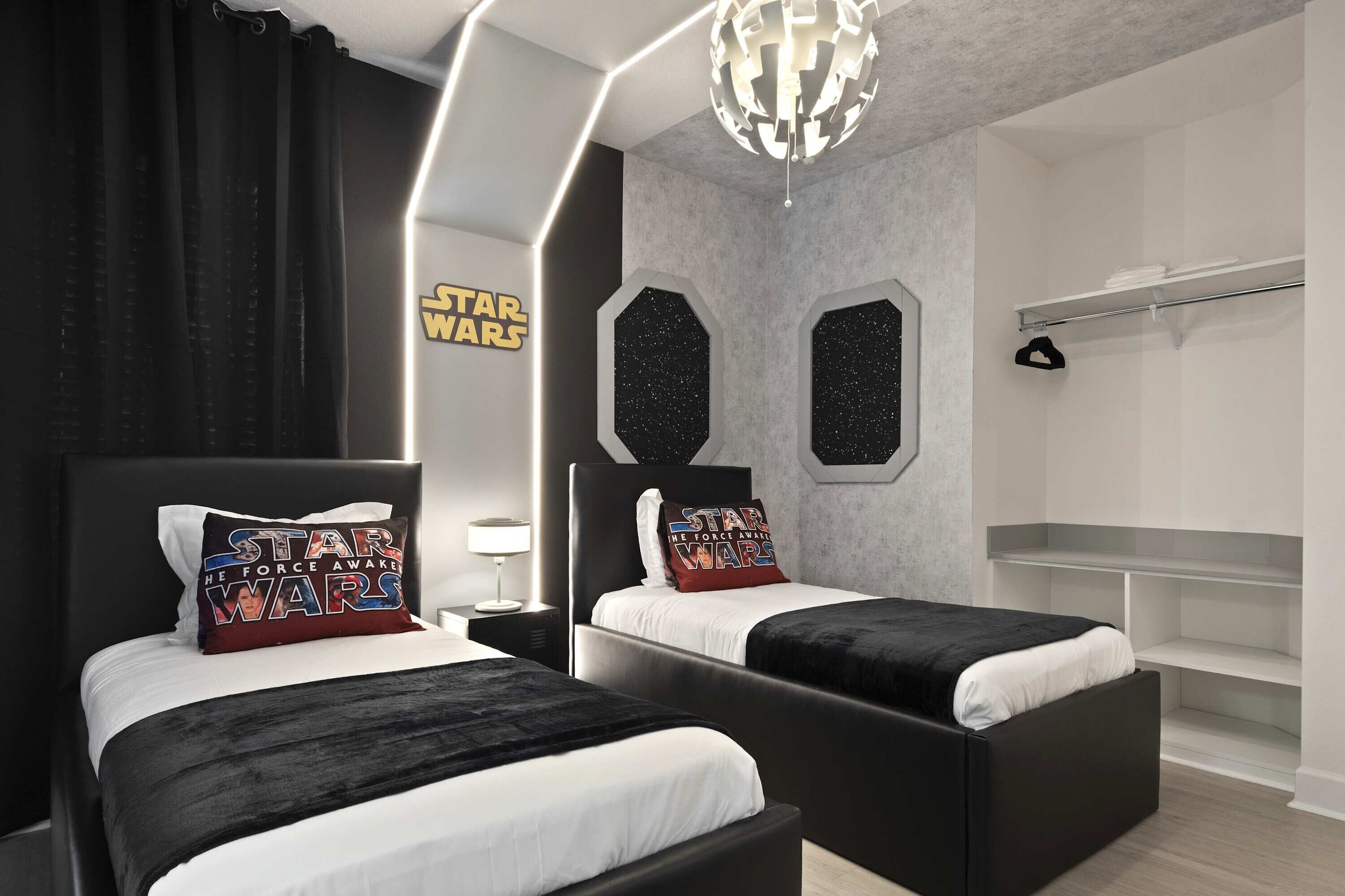 Ein modernes Schlafzimmer mit zwei Betten, Kissen und einem Schild im Stil von Star Wars sowie einer einzigartigen geometrischen Deckenleuchte.