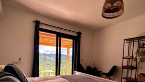 Ein Schlafzimmer mit Bett, Schreibtisch und Blick ins Freie.
