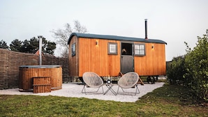 A wooden cabin with a door, two chairs, a table, and a trash bin. - Shepherds View (Ashbourne)