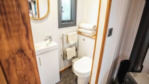 A compact bathroom with a white sink, a toilet, and a mirror. - Shepherds View (Ashbourne)