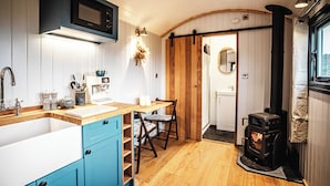 A kitchen with a microwave, coffee machine, sink, and wooden cabinets. - Shepherds View (Ashbourne)