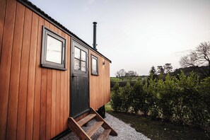 A wooden building with a black door, windows, and a chimney. - Shepherds View (Ashbourne)