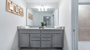 A bathroom with a double vanity, a large mirror, and a ceiling light fixture. - Last Minute Disney Getaway! Private Pool, Game Room & Themed Bedrooms. Book Now! #163645 (Orlando)