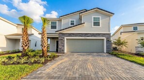 A two-story house with a garage, a stone facade, and a paved driveway. - Last Minute Disney Getaway! Private Pool, Game Room & Themed Bedrooms. Book Now! #163645 (Orlando)