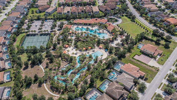 Ovenfra ses et boligområde med en central swimmingpool, tennisbaner og en anlagt park.