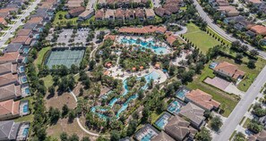 An aerial view of a residential area with a central swimming pool, tennis courts, and a landscaped park area. - Last Minute Disney Getaway! Private Pool, Game Room & Themed Bedrooms. Book Now! #163645 (Orlando)