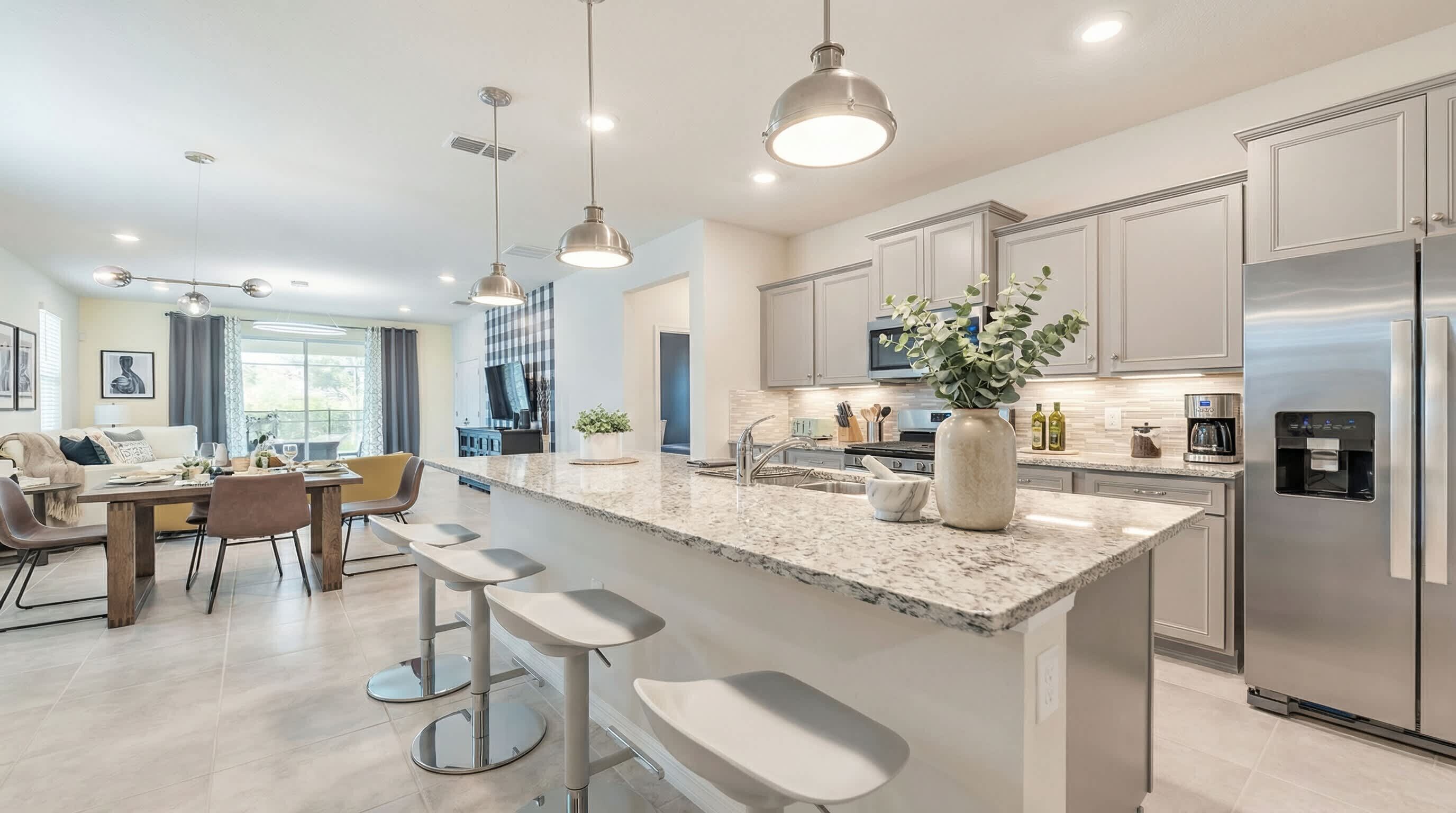A modern kitchen with a large island, stainless steel appliances, and pendant lighting.