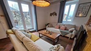 A living room with a sofa, a coffee table, and a television. - Charming “La Ferme du Château” – Private Terrace, Peaceful Setting, Fresh Air (Venon)