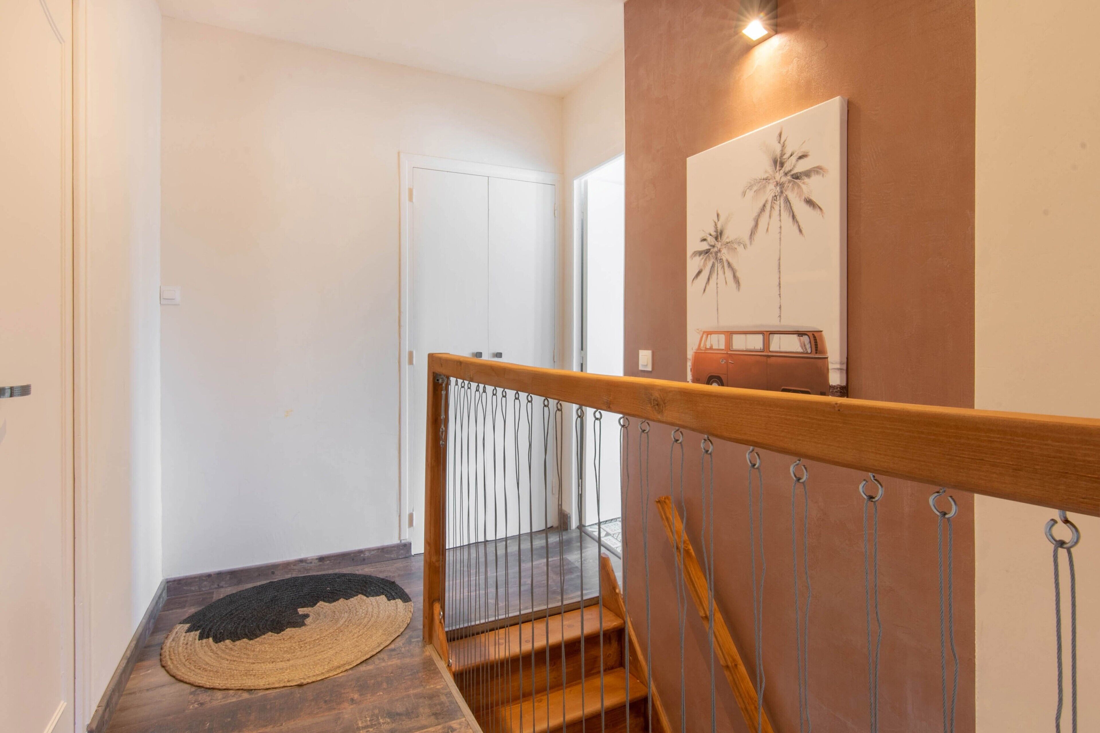 A staircase with a wooden handrail and metal balusters, leading to a room with a white door and a wall-mounted artwork.