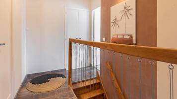 Eine Treppe mit Holzhandlauf und Metallspindeln, die zu einem Raum mit einer weißen Tür und einem an der Wand befestigten Kunstwerk führt.