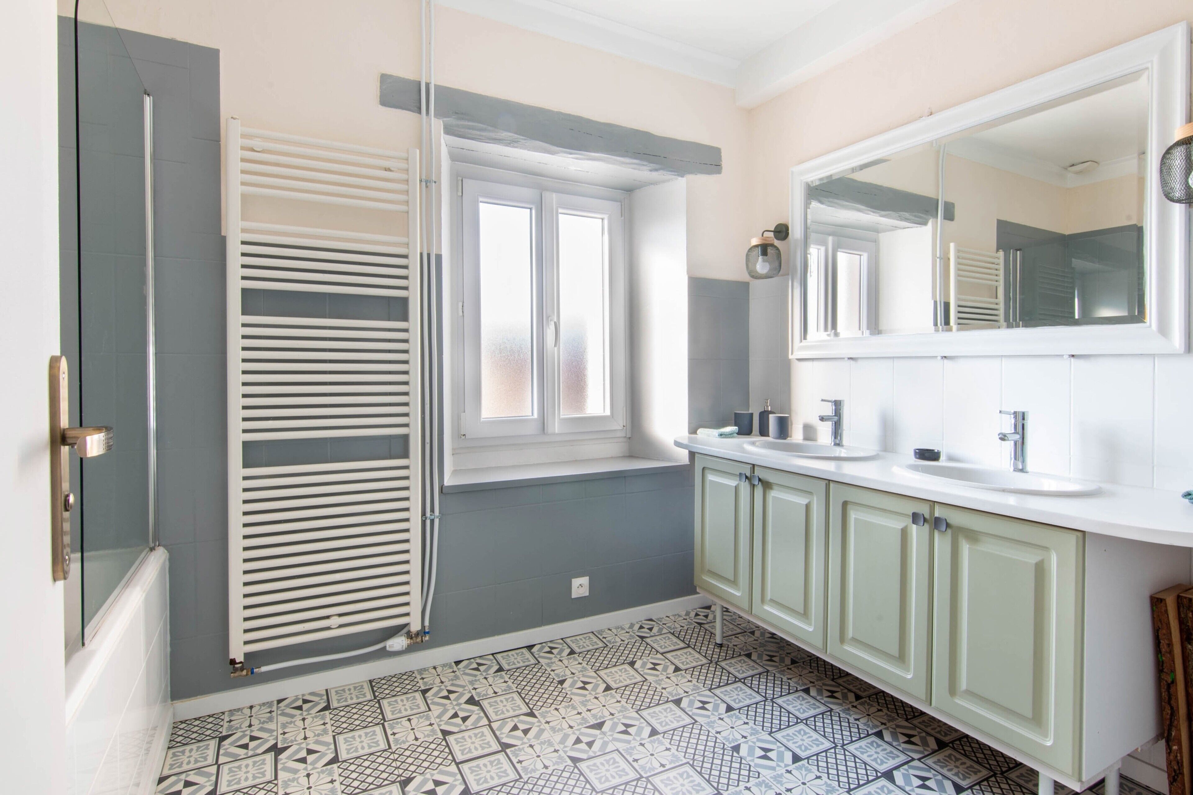 Een badkamer met een douche, een raam, een wastafel en een spiegel.