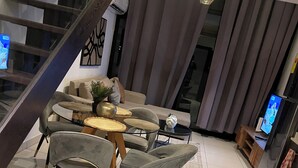 Una sala de estar moderna con comedor, una escalera y una cocina.