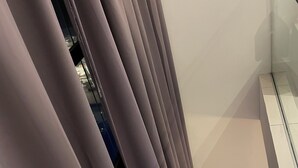 Una habitación con un ventanal grande, un mueble bajo de madera para la televisión y una cortina.