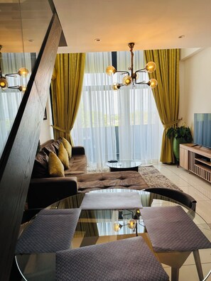 A modern living room with a glass coffee table, leather sofa, and a TV stand. - danny's lux home  (Accra)
