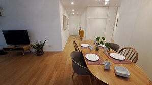 Ein Essbereich mit Holztisch, Stühlen und einem Fernseher in der Ecke.