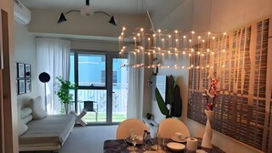 Un comedor moderno con una mesa lista para dos, un sofá y un balcón con vistas.