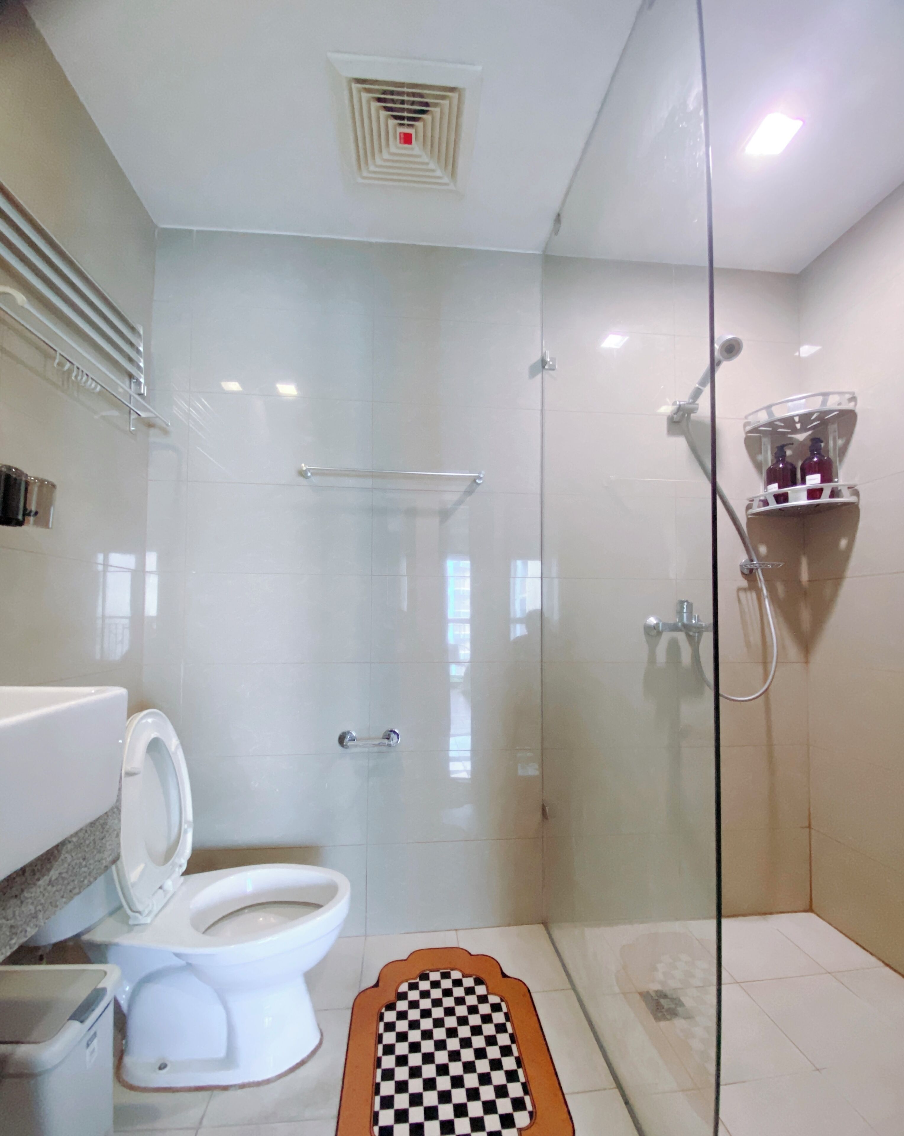 Une salle de bain moderne dotée d’une douche à parois de verre, de toilettes et d’un lavabo.