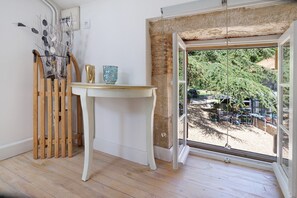 Une piĂšce dotĂ©e dâun plancher en bois, dâune table blanche et offrant une vue sur un espace extĂ©rieur grĂące Ă une grande fenĂȘtre.