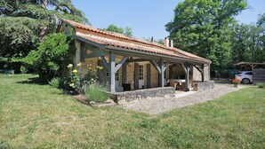 A rustic outdoor structure with a tiled roof, stone walls, and a covered patio area.