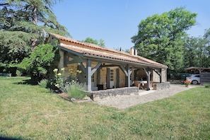Une structure extĂ©rieure rustique, dotĂ©e dâun toit en tuiles, de murs en pierre et dâun patio couvert.