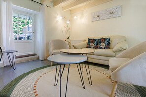 A living room with a sofa, two armchairs, a coffee table, a door with curtains, and a radiator. - Charming Detached Stone House with Private Pool in the Heart of Périgord, No Overlook (Limeyrat)