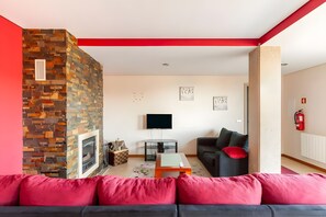 Een woonkamer met een open haard, een flatscreen televisie, een bank en een salontafel.