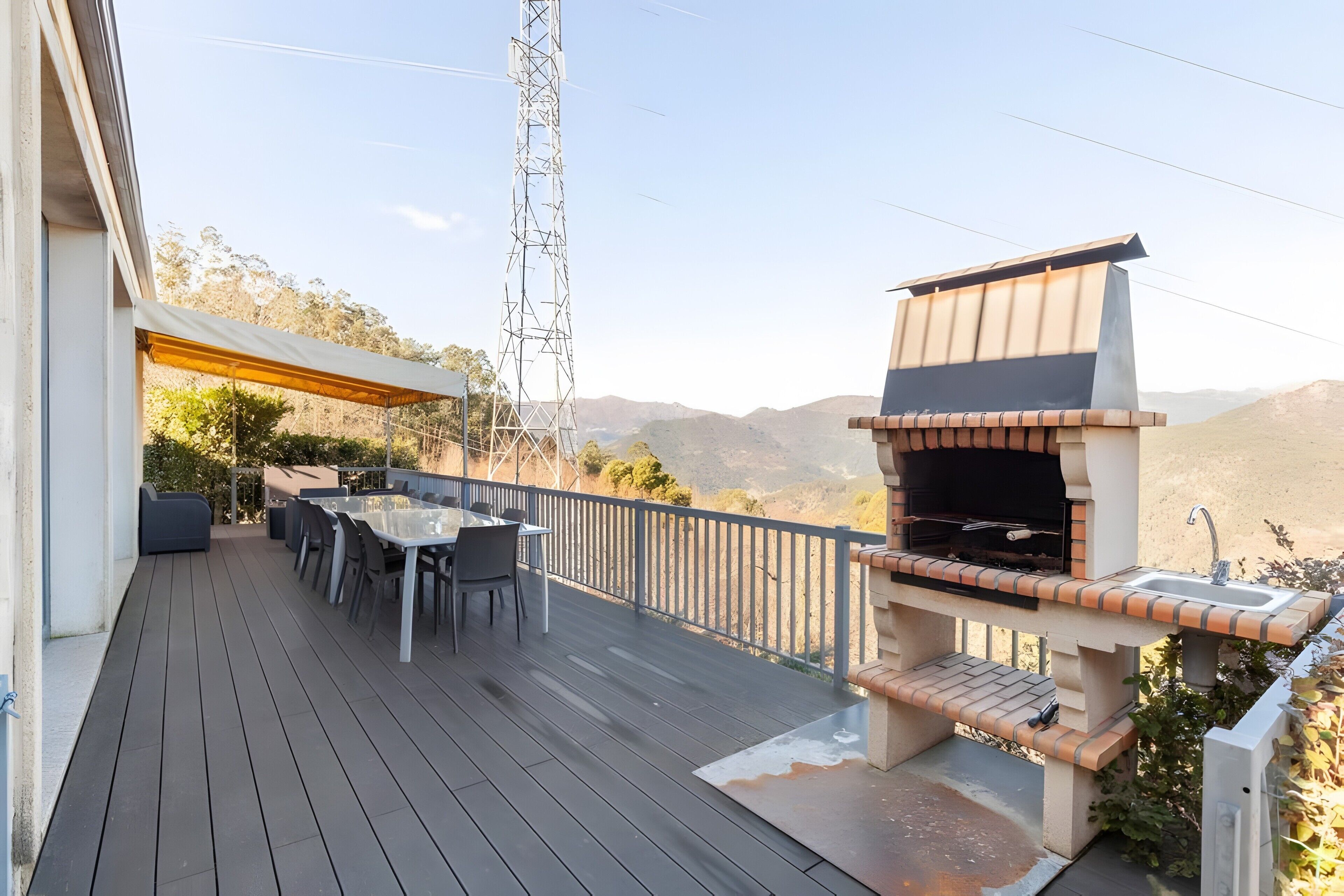 A deck with outdoor furniture, a barbecue grill, and a view of the mountains.