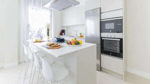 A modern kitchen with white cabinetry, a central island with seating, a built-in oven, and a stainless steel refrigerator. - Comfortable Family Stay by the Sea (Aguimes)