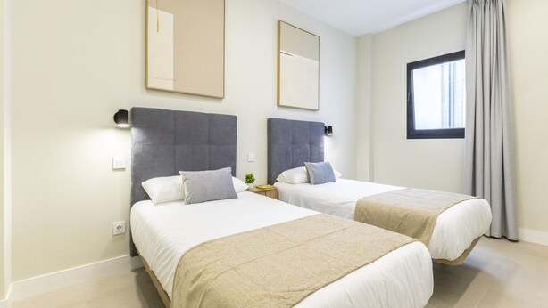 A hotel room with two beds, a large window with curtains, and two wall-mounted mirrors. - Comfortable Family Stay by the Sea (Aguimes)