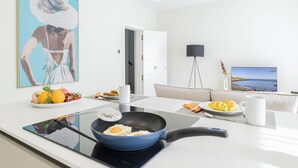 A modern kitchen with a stove, a bowl of fruit, and a painting of a woman. - Comfortable Family Stay by the Sea (Aguimes)