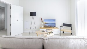 A modern living room with a sofa, a coffee table, a TV, and a floor lamp. - Comfortable Family Stay by the Sea (Aguimes)